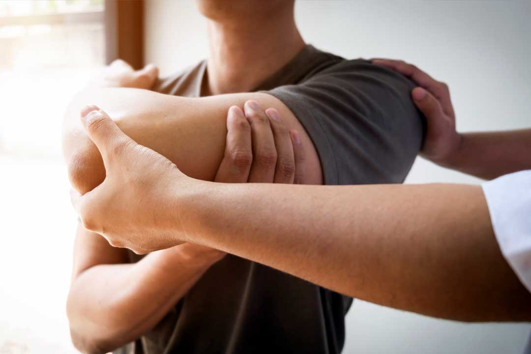 Therapist treating a male injured by rotator cuff stretching