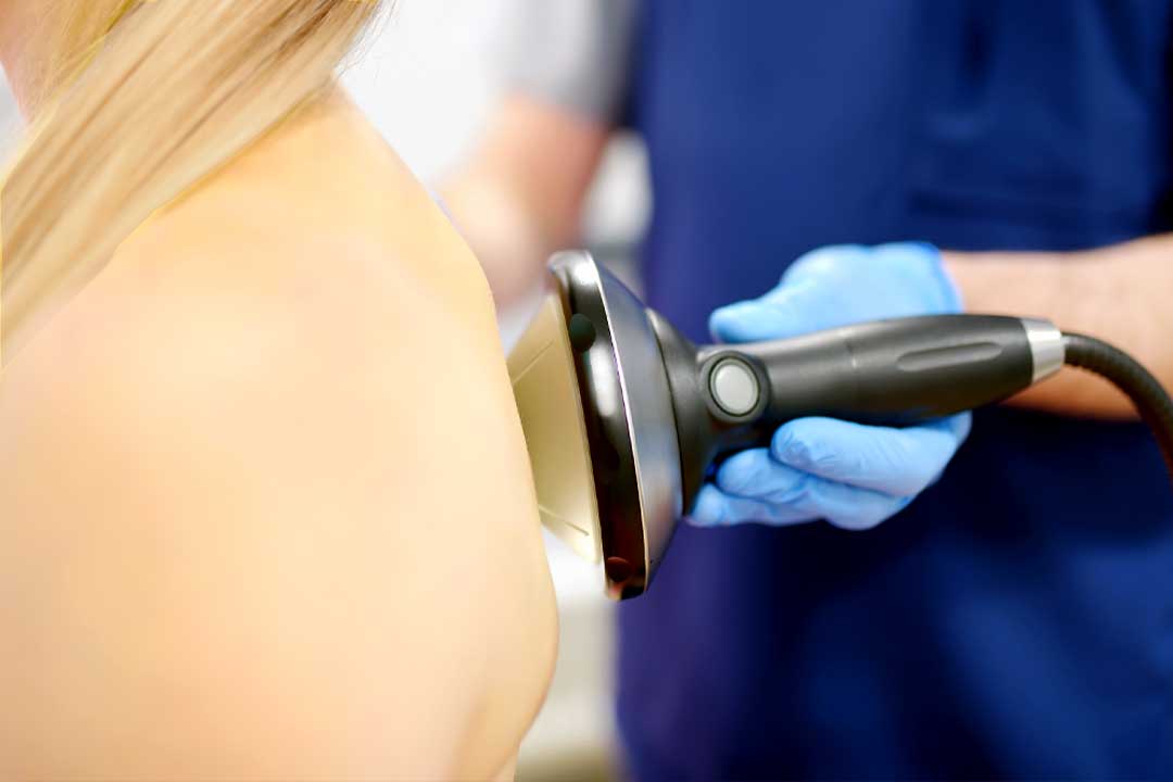 Woman receiving focused shockwave therapy on her back and shoulder